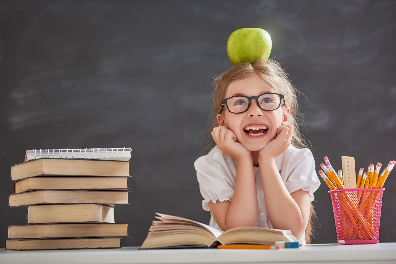 Niña en clase con gafas para leer.