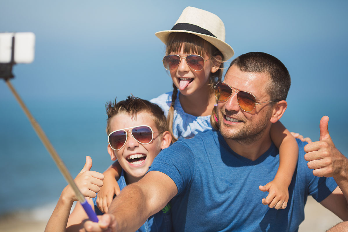 Padre con niños en la playa y todos con gafas de sol.