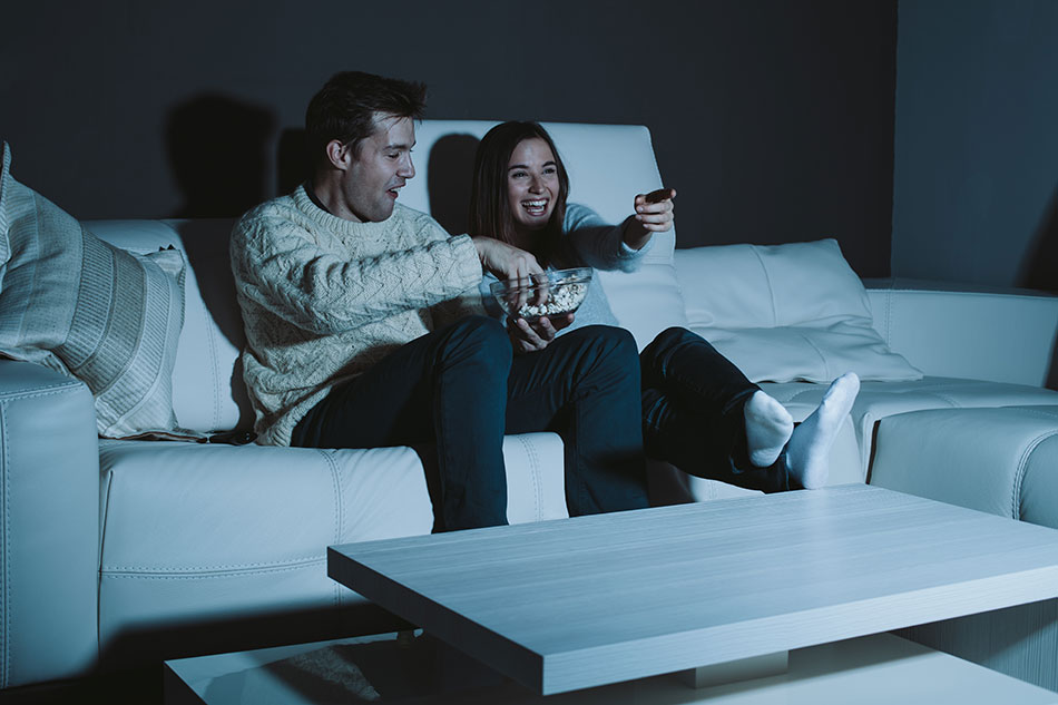 Pareja de jovenes viendo la televisión a oscuras