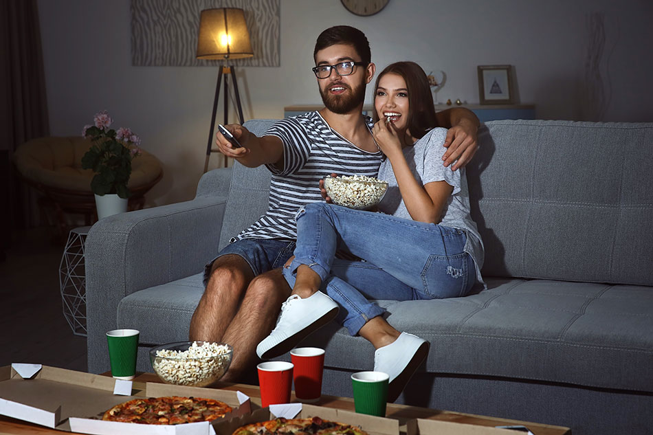 Pareja viendo la televisión por la noche con luz ambiente