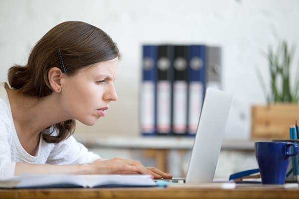 Mujer sin la promoción de lentes progresivas ocupacionales frente al ordenador forzando la vista