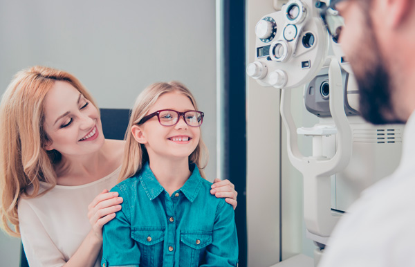 Niña con su madre haciendo revisión en la óptica