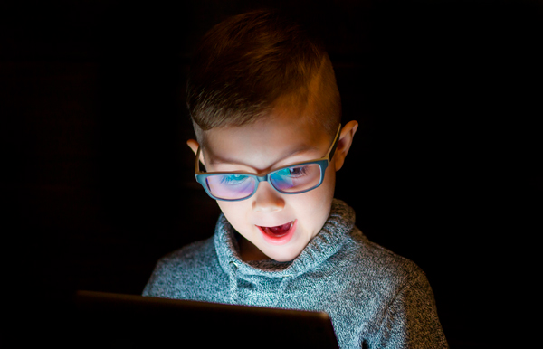 Niño mirando a una pantalla con lentes con filtro de luz azul