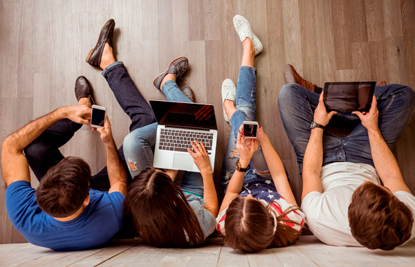 Jóvenes con móviles, portátiles, pantallas, tablets