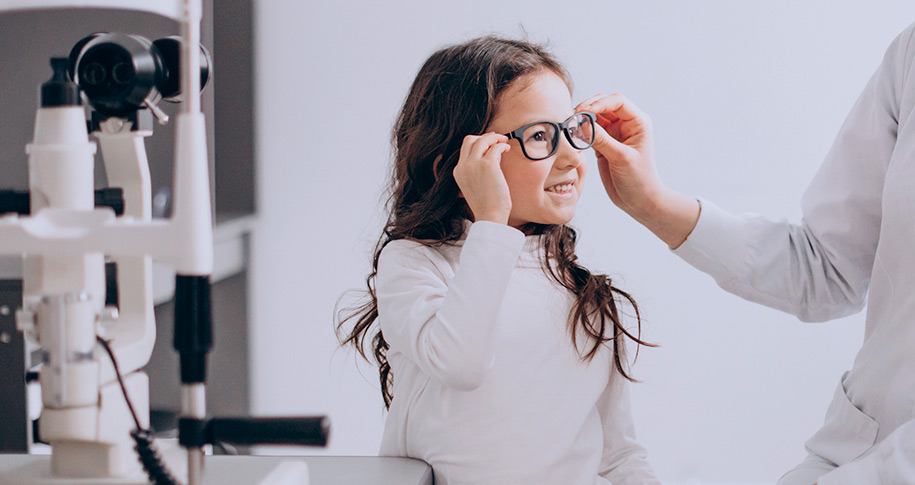 Niña feliz probándose gafas en la óptica