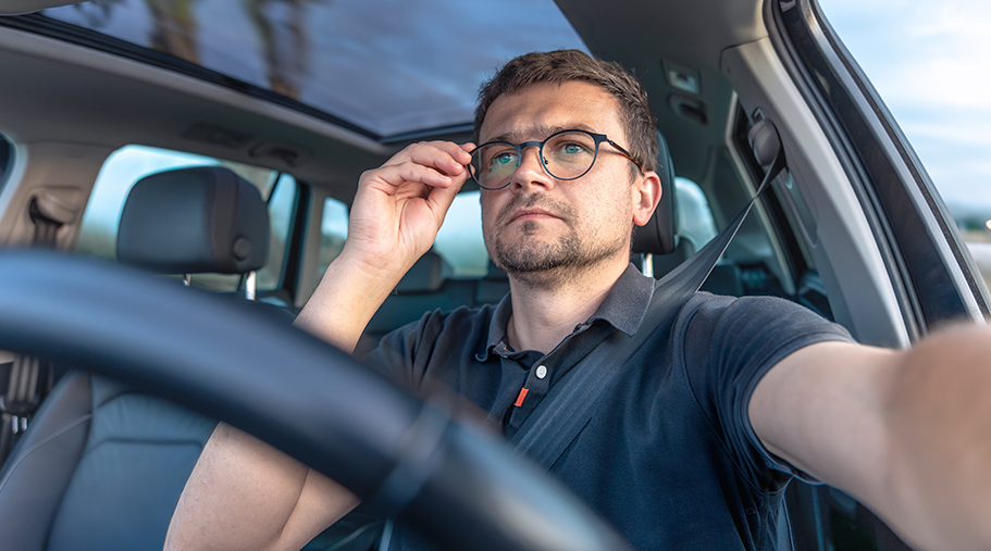 Chico de mediana edad con dificultad para ver conduciendo.