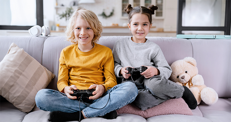 Dos niños jugando a videojuegos en el sofá